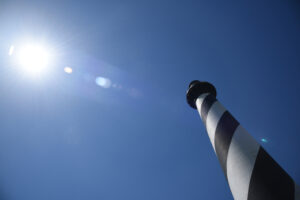 The Cape Hatteras Lighthouse stands as a beacon along the Outer Banks. The sun is lined up perfectly with the lighthouse.