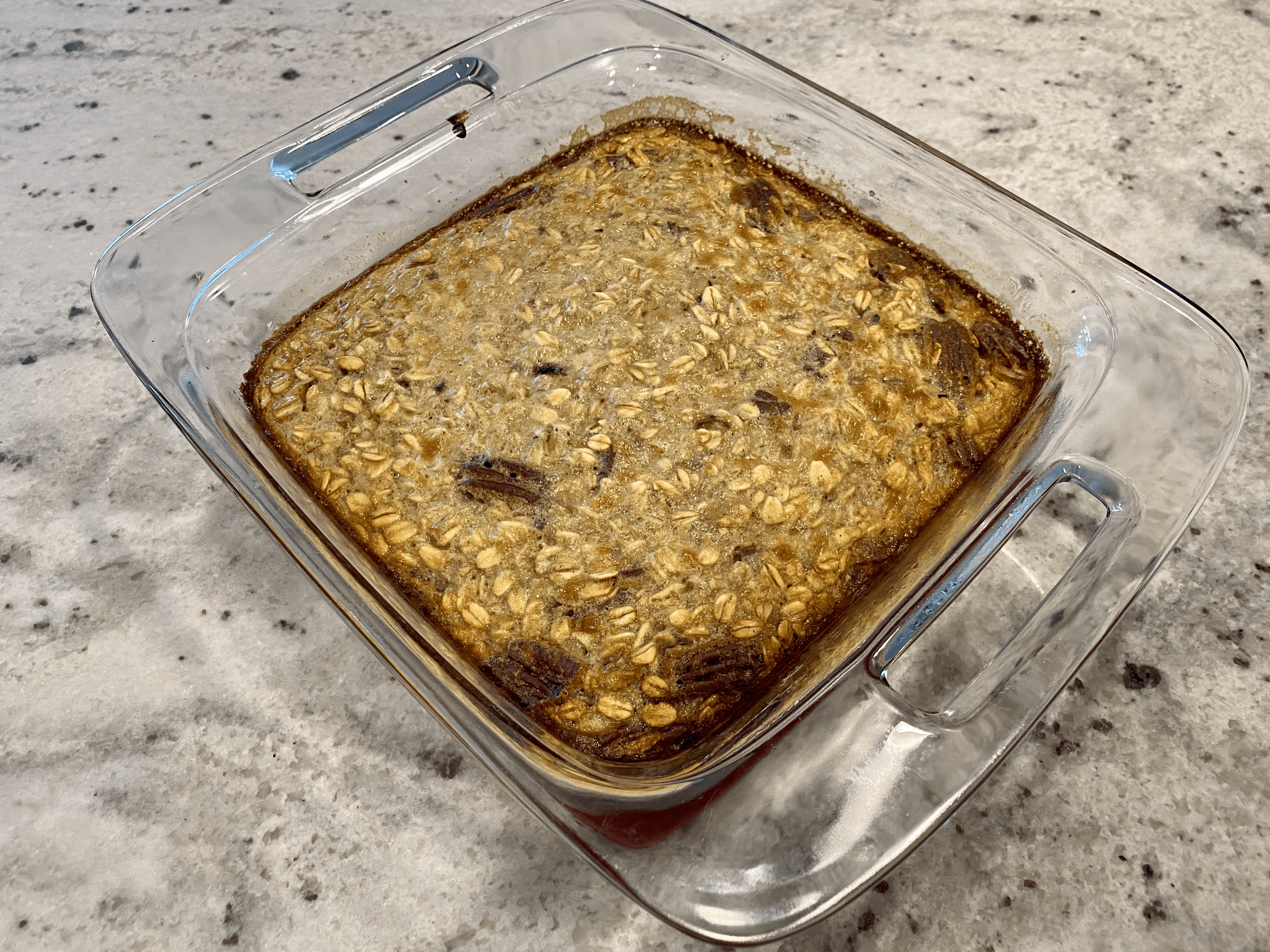 Baked Banana Bread Oatmeal in a Glass Dish on a Marble Countertop