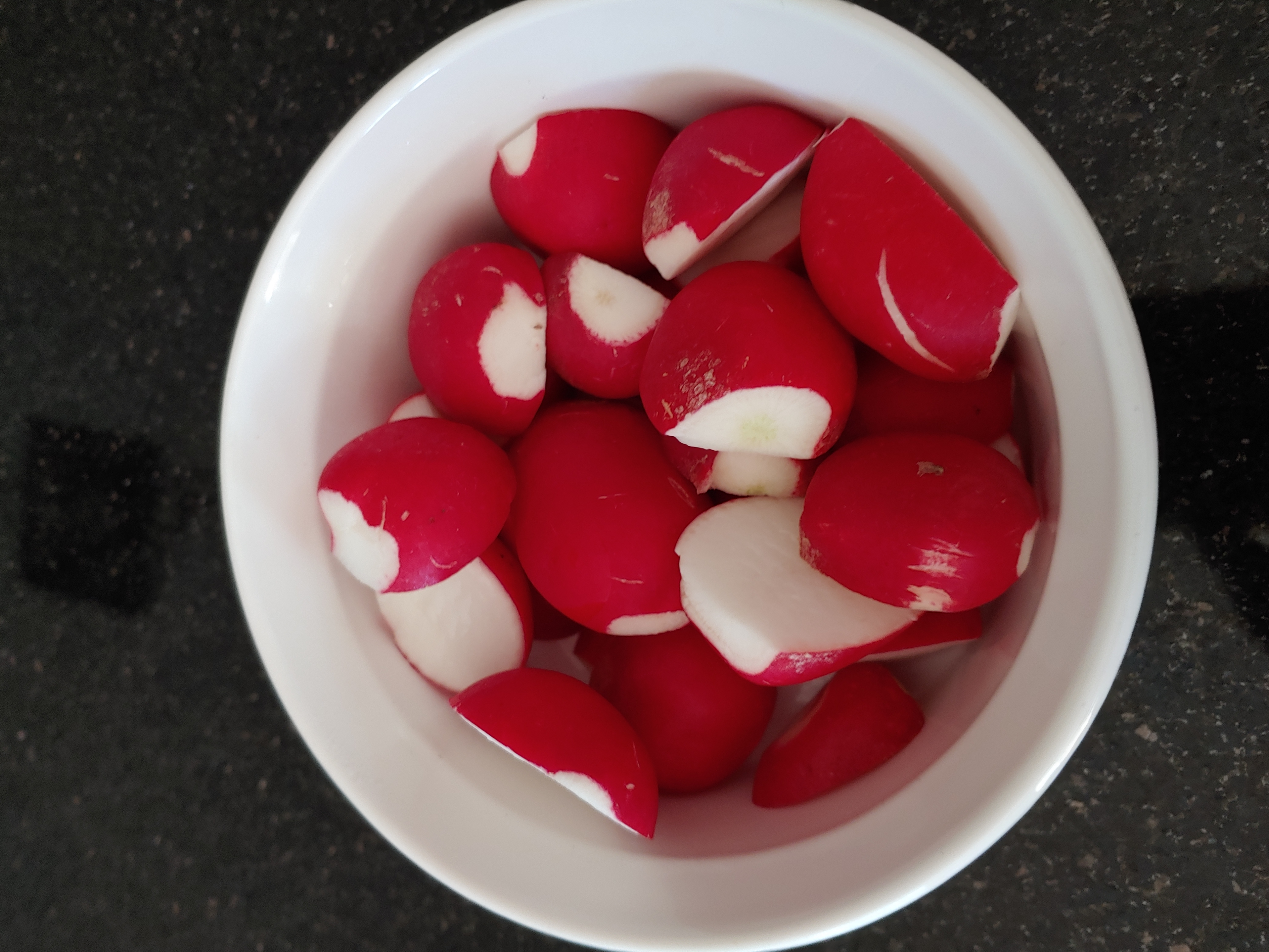 cut raw radishes in a white bowl