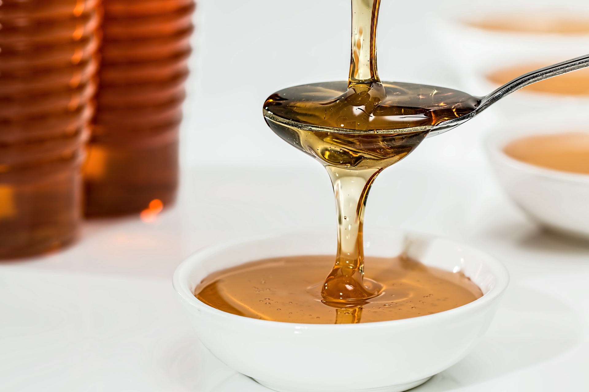 honey being poured over a spoon into a white bowl