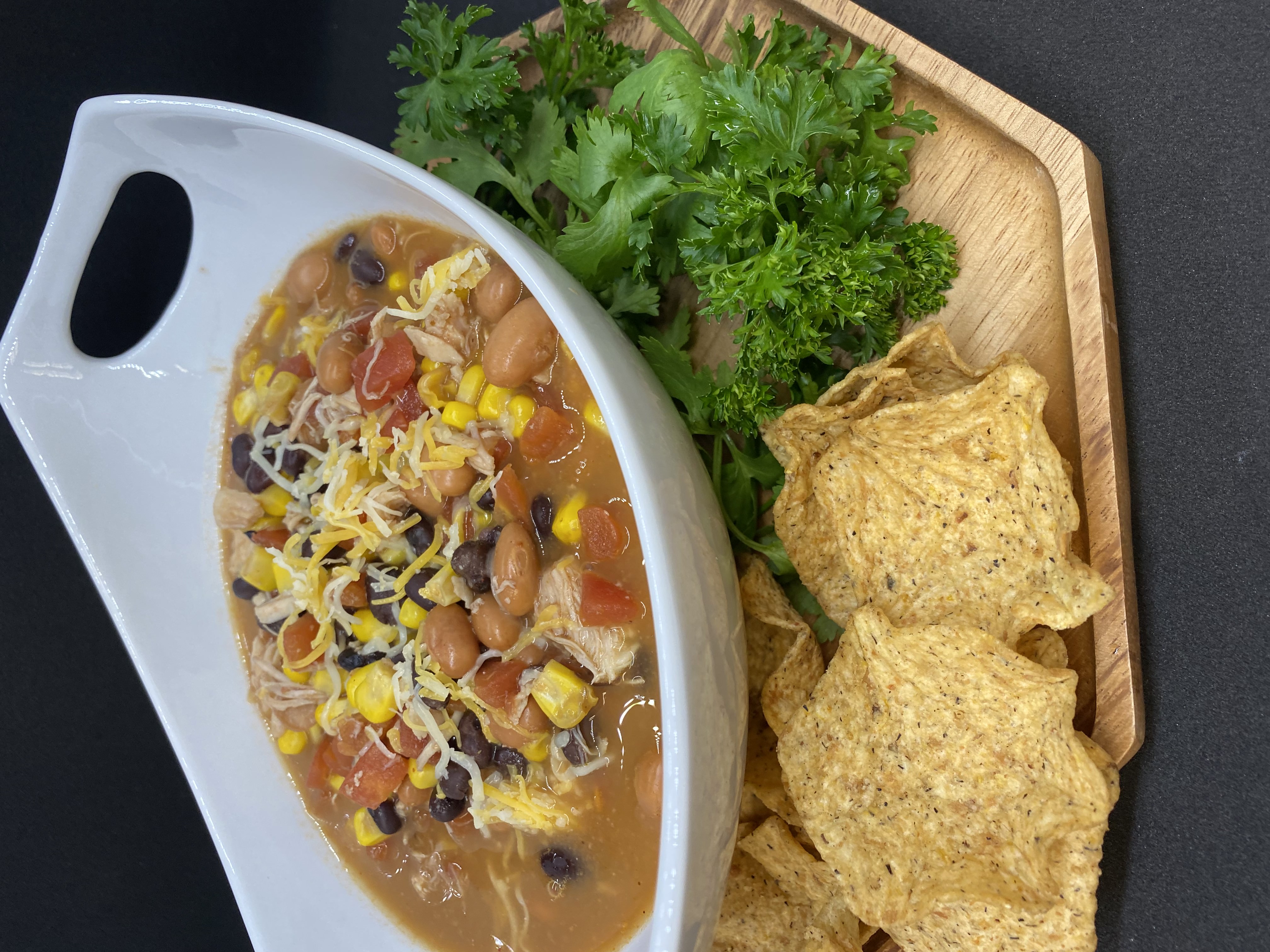 chicken tortilla soup plated with tortilla chips and topped with cheese
