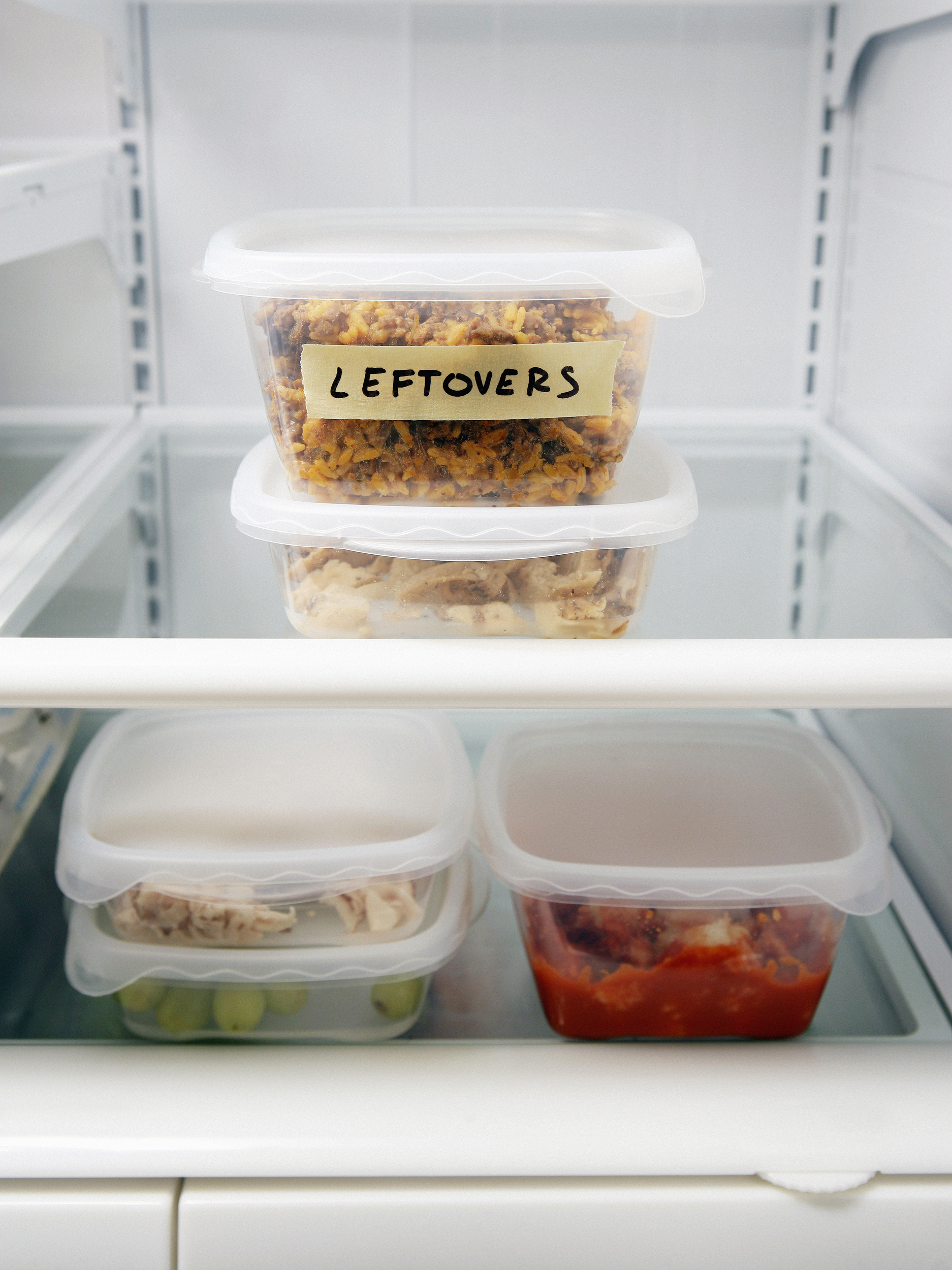 A refrigerator with plastic containers labeled leftovers.