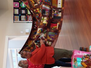 An African American woman displays her quilt.