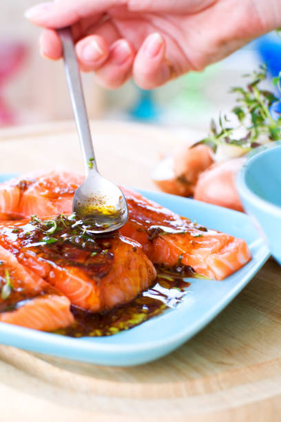 person spoons sauce onto a salmon dish