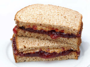 Stacked peanut butter and jelly sandwiches on 100% whole wheat bread.