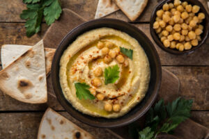 healthy homemade chickpea hummus with olive oil and smoked paprika, wooden background, top view