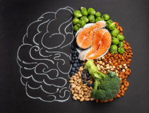Chalk hand drawn brain with assorted food, food for brain health and good memory: fresh salmon fish, green vegetables, nuts, berries on black background. Foods to boost brain power, top view