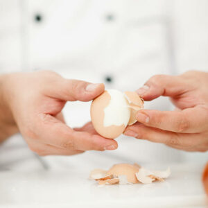 Chef peeling boiled egg in domestic kitchen / close-up shot / focus on egg