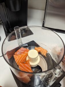 salmon placed in a food processor for chopping and mixing.