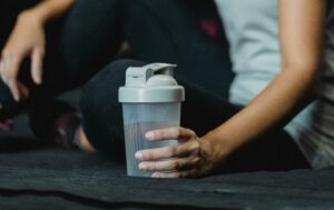 shaker bottle filled with water being held by a lady in a gym