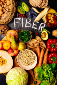 Foods rich in fiber as rye galette , wheat bran, beans , almonds, seed, pears, plum bananas, cranberry, raspberries, pistachios, red pepper kiwi walnuts melon celery carrot Wooden table as background