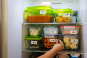 Food leftovers packaged in boxes inside a home fridge with dates written on.