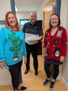 Three people pose together with cookies.