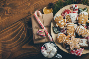 Plate with Christmas cookies on wooden table with cup of hot chocolate and gifts