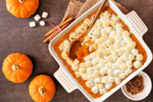 Sweet potato casserole with toasted marshmallows. Top down view table scene on a dark stone background. Thanksgiving food concept.