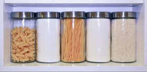 Kitchen jars on a shelf with Macaroni, Sugar, Spaghetti, Flour and Rice