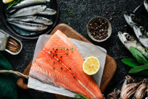 Raw salmon steak with herbs and spices on table. Top view of fresh fish and seafood on kitchen counter.